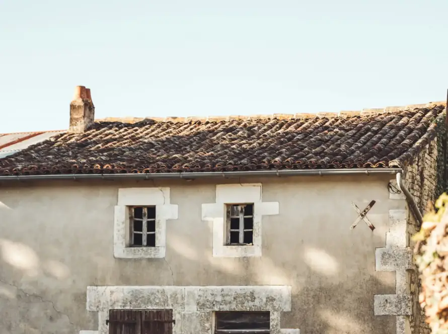 Vecchio rustico in pietra da ristrutturare, con intonaco scrostato, finestre murate e crepe sulla facciata